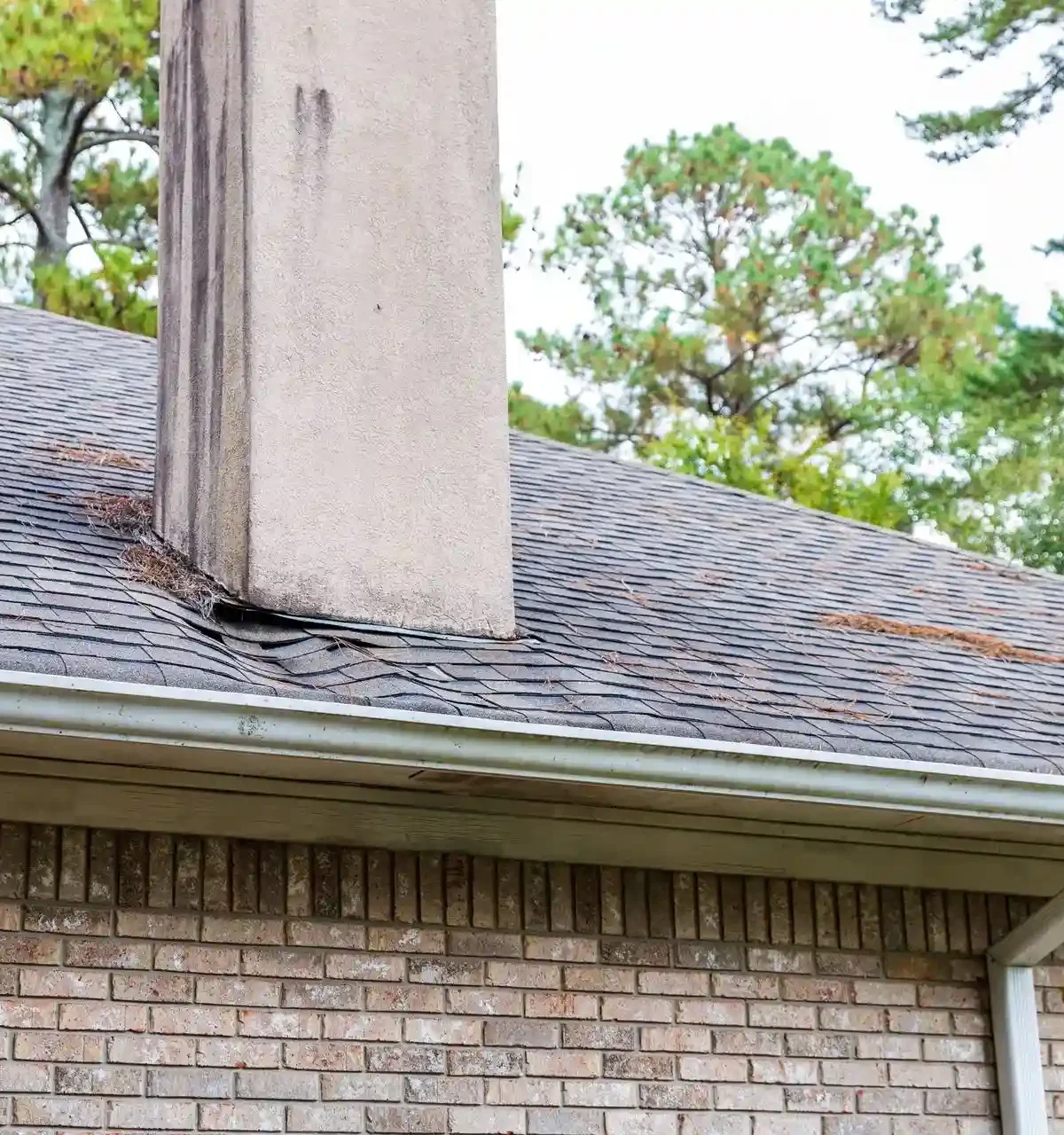 An employee is perched on a step ladder doing routine home maintenance for rain gutters